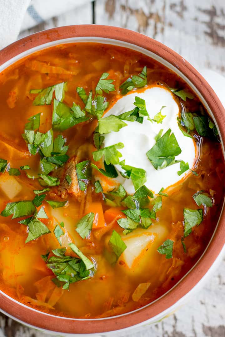 Russian cabbage soup with beef, topped with sour cream and parsley.
