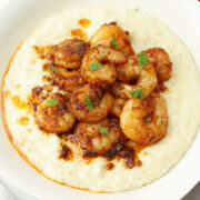 A white bowl filled cajun shrimp and grits.