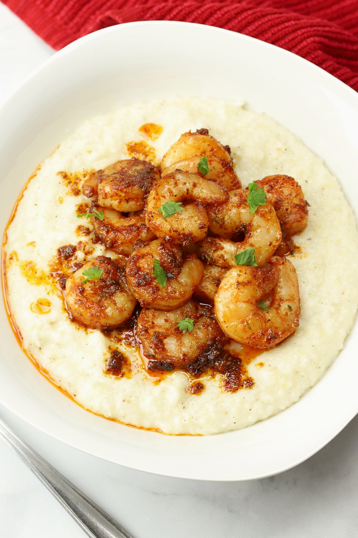 A white bowl filled cajun shrimp and grits.