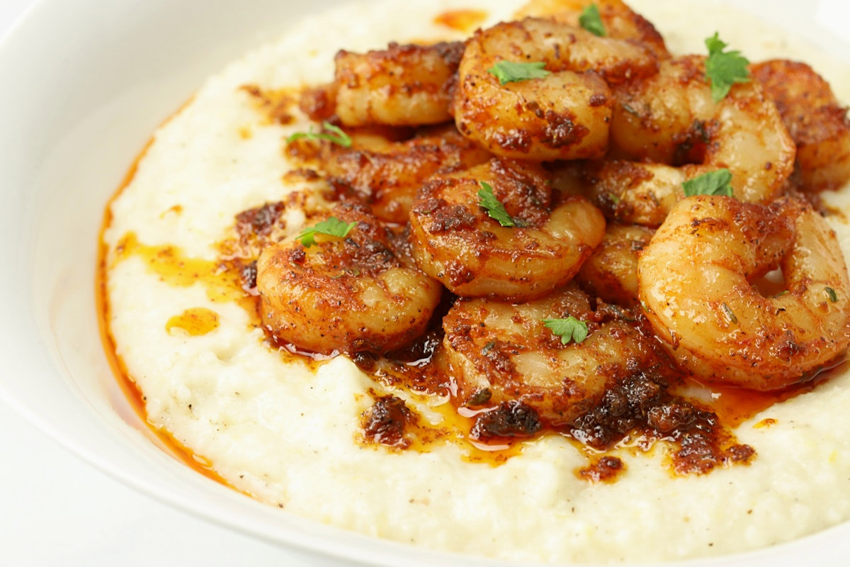 A close up of Cajun shrimp on top of a bowl of grits.