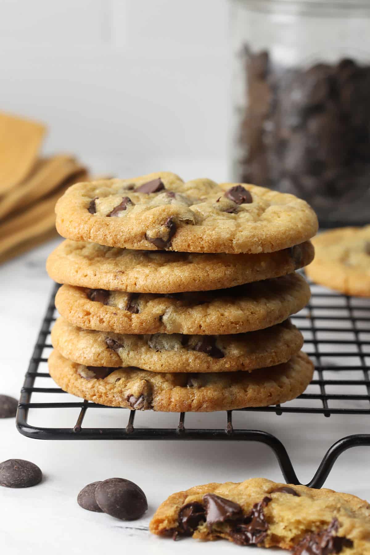 A stack of chocolate chip cookies on the edge of a cooling rack.