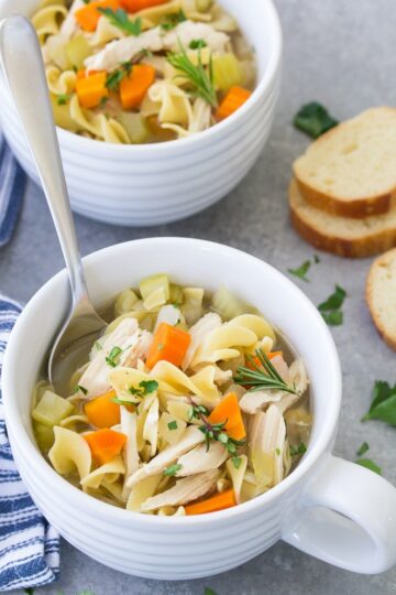 Chicken noodle soup in white soup bowls.