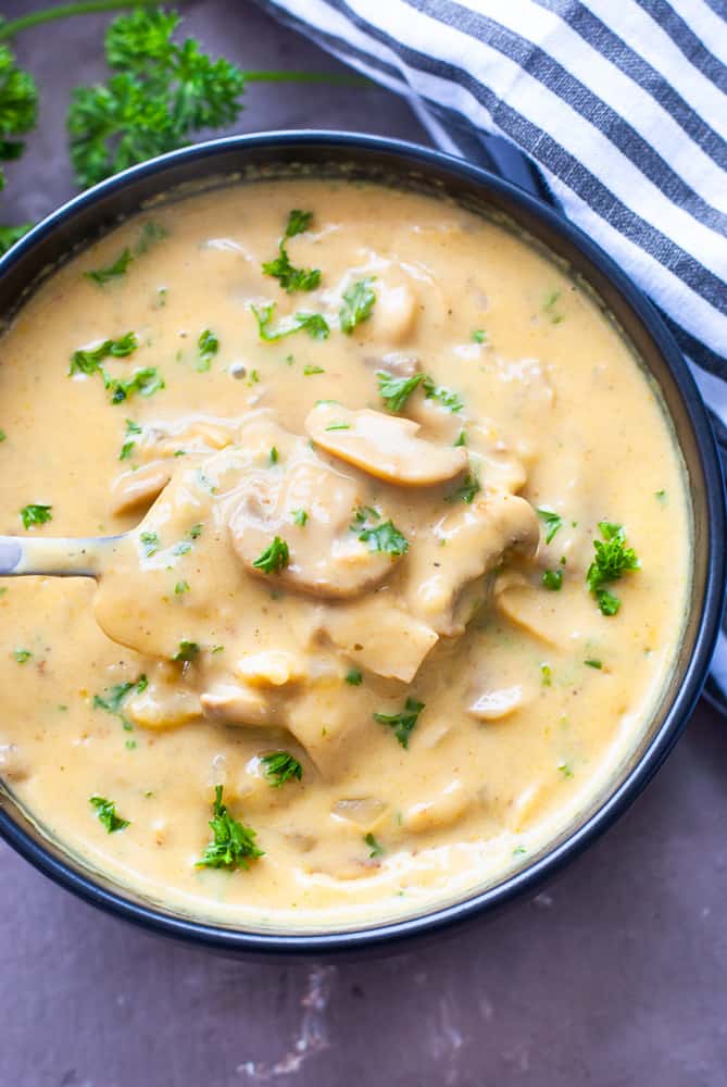 Soup filled with mushrooms, topped with parsley.