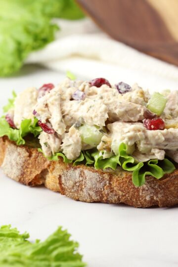 A slice of bread, lettuce, and a scoop of chicken salad.