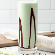 A highball glass filled with frozen grasshopper with swirls of chocolate sauce on the sides of the glass.