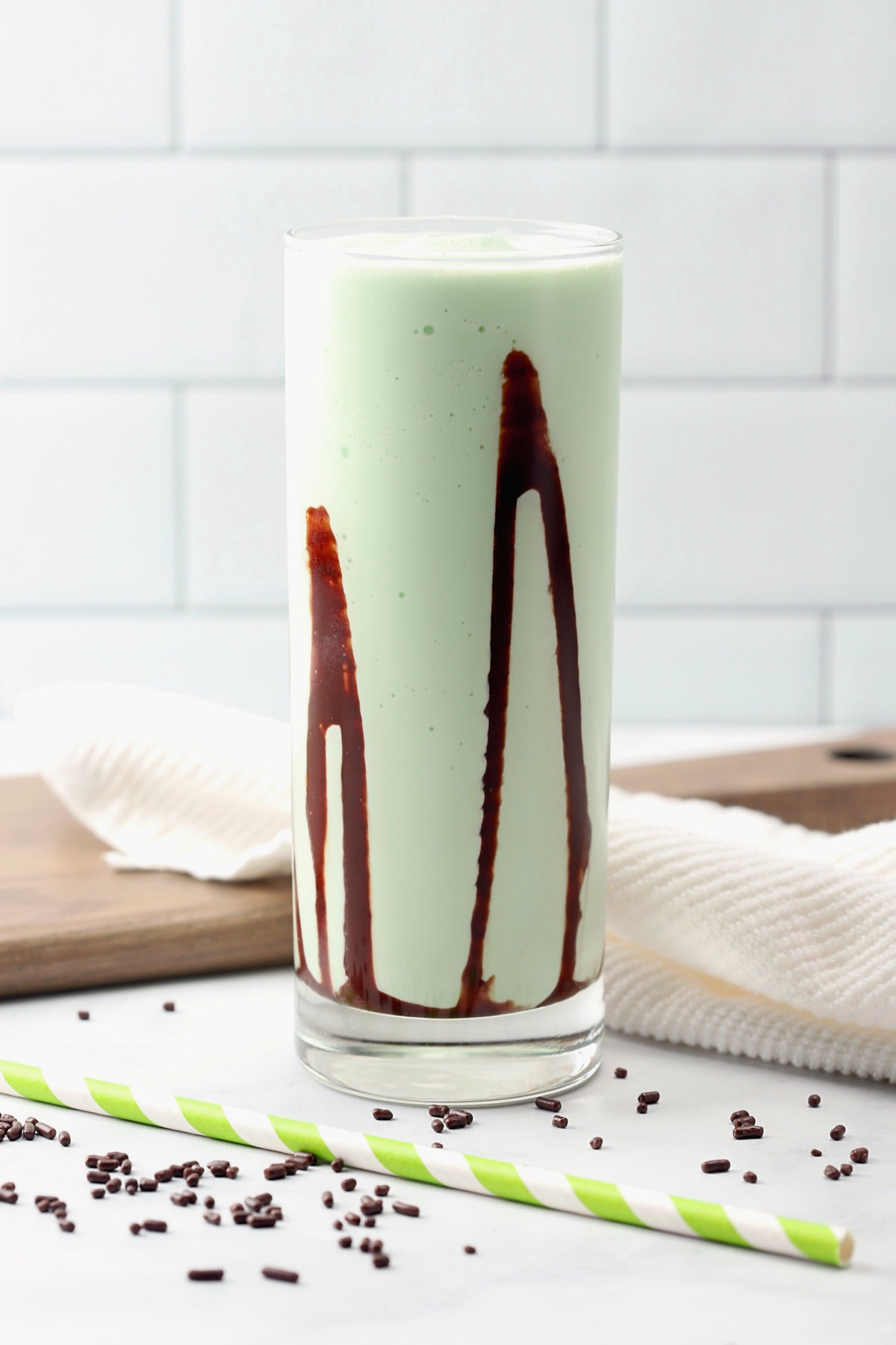 A highball glass filled with frozen grasshopper with swirls of chocolate sauce on the sides of the glass.