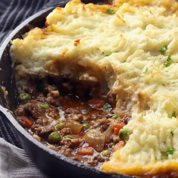 A cast iron pan filled with beef cottage pie and potatoes.