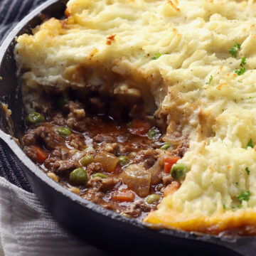 A cast iron pan filled with beef cottage pie and potatoes.