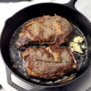 Cast iron pan with two steaks.