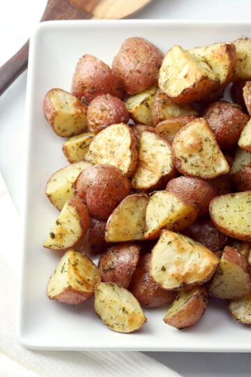 Quartered red potatoes coated in ranch seasoning on a serving plate.