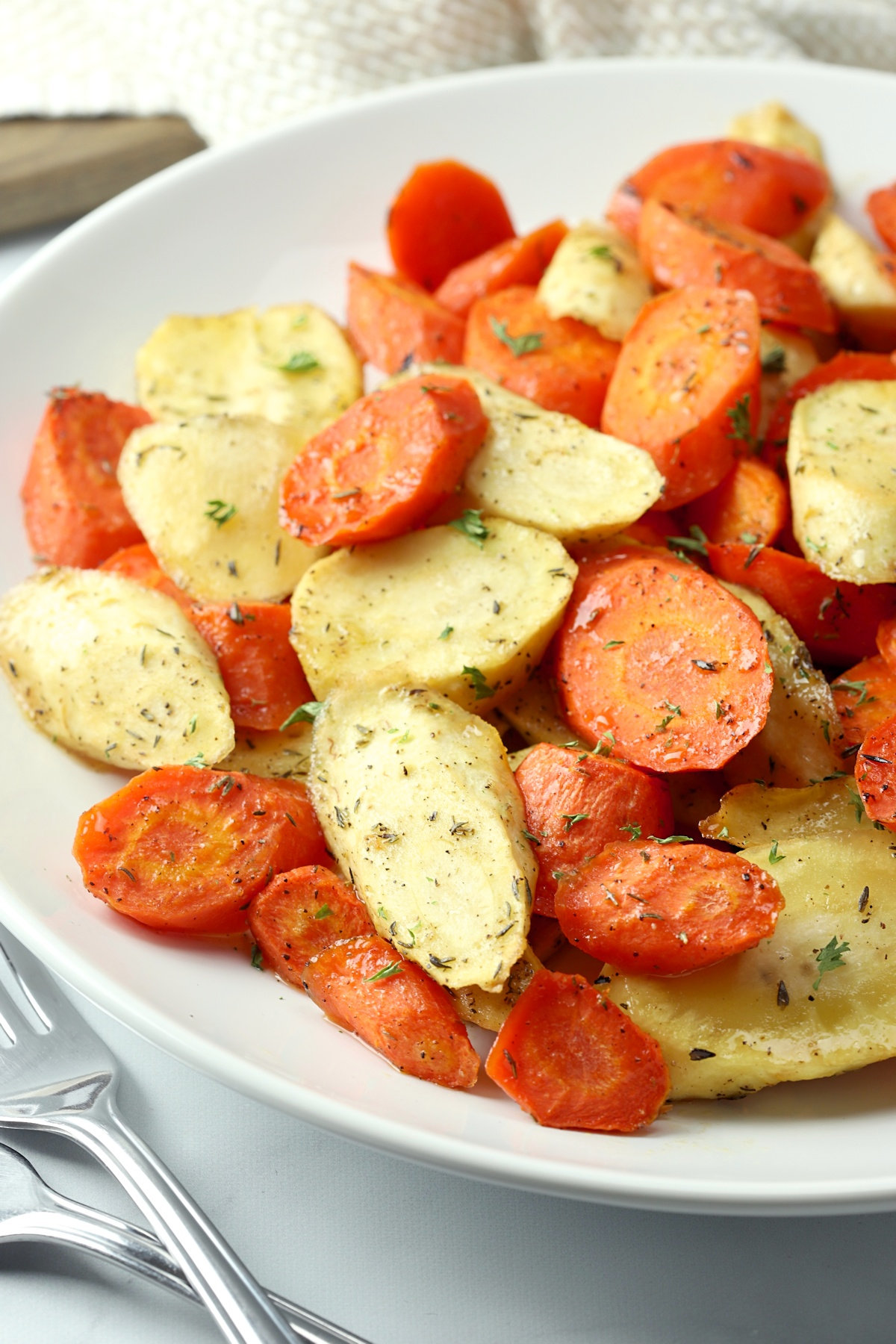 Close up of roasted parsnips and carrots on a serving plate.