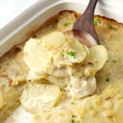A wooden spoon scooping a serving of scalloped potatoes.