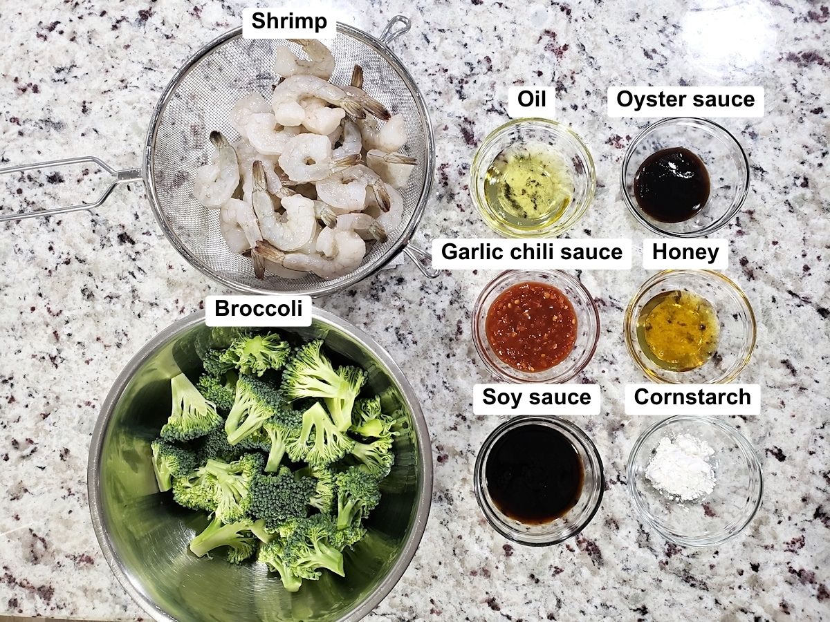 Shrimp, broccoli, and seasonings on a counter top.