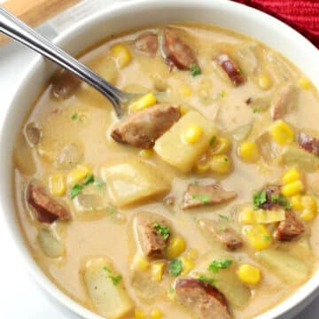 A white bowl filled with corn chowder with andouille sausage.