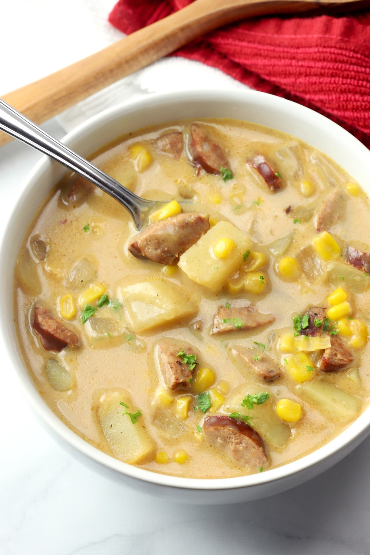 A white bowl filled with corn chowder with andouille sausage.