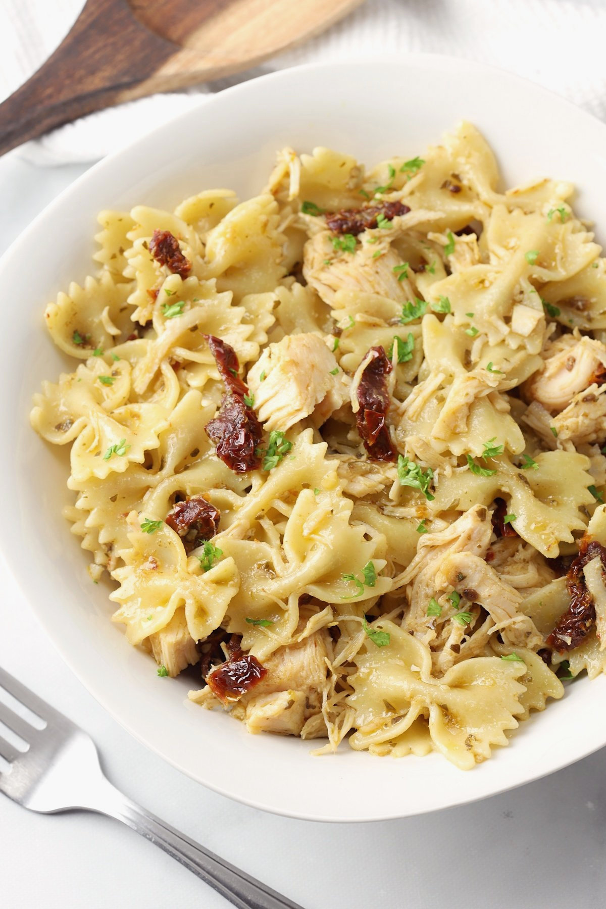 A white bowl filled with bow tie pasta and chicken.