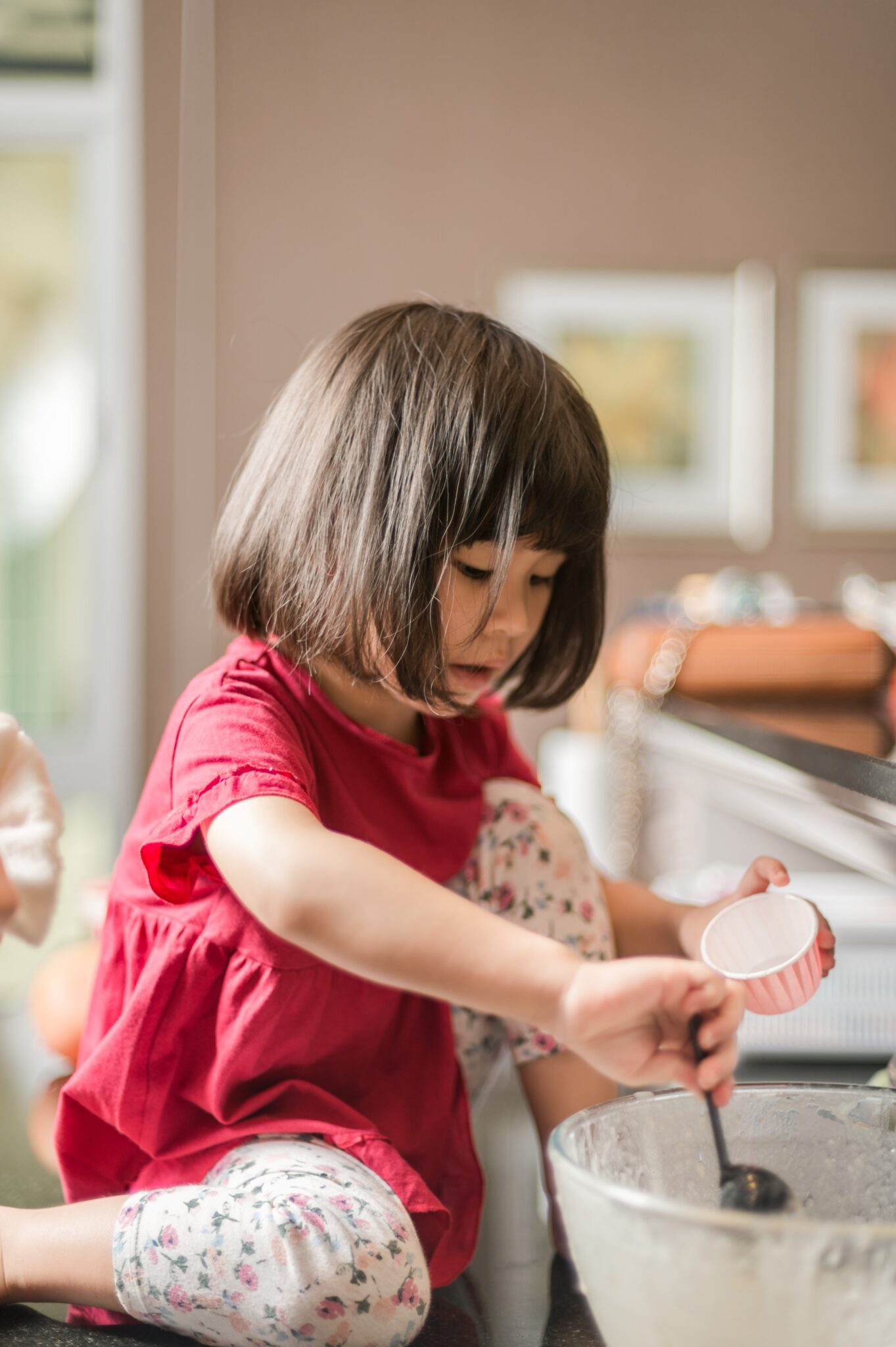 Girl in red t-shirt is helping bake cupcakes at home.