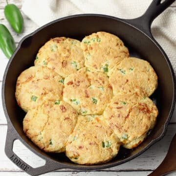 A cast iron skillet filled with jalapeno cheddar biscuits.
