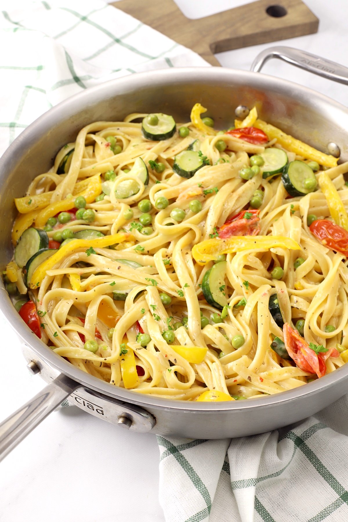 A saute pan filled with creamy pasta primavera with bright summer vegetables.