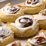Close up of cinnamon rolls on a sheet pan covered with icing.