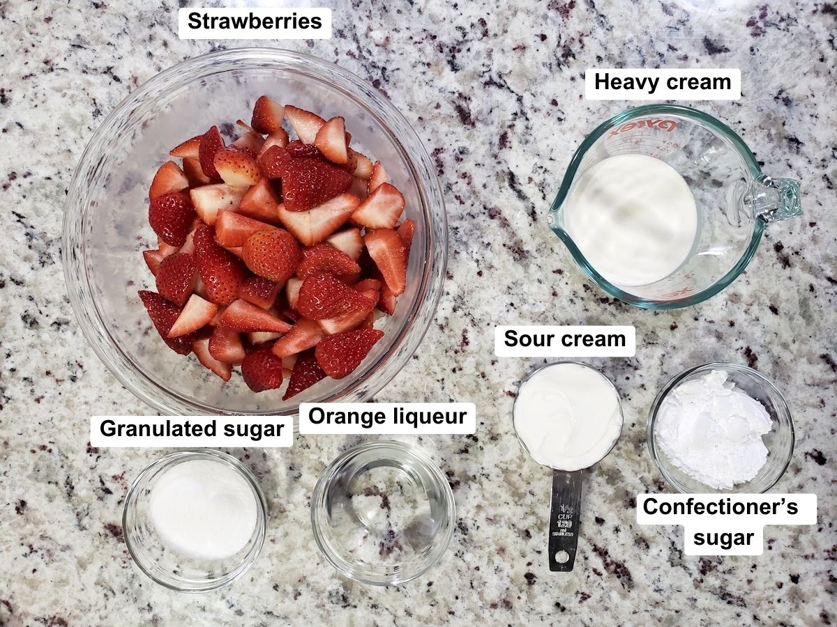 Ingredients to make strawberries romanoff on a marble counter top.