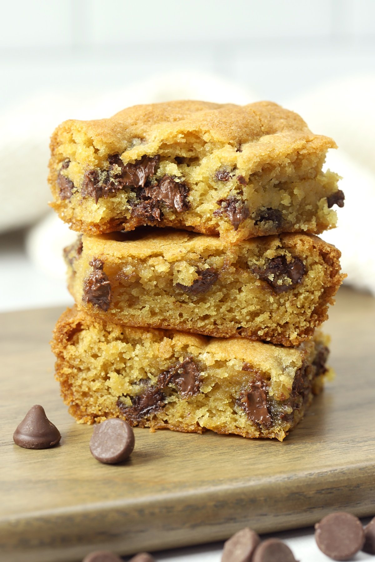 Stack of chocolate chip cookie bars on a wood cutting board.