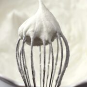A whisk with a dollop of whipped cream on top.