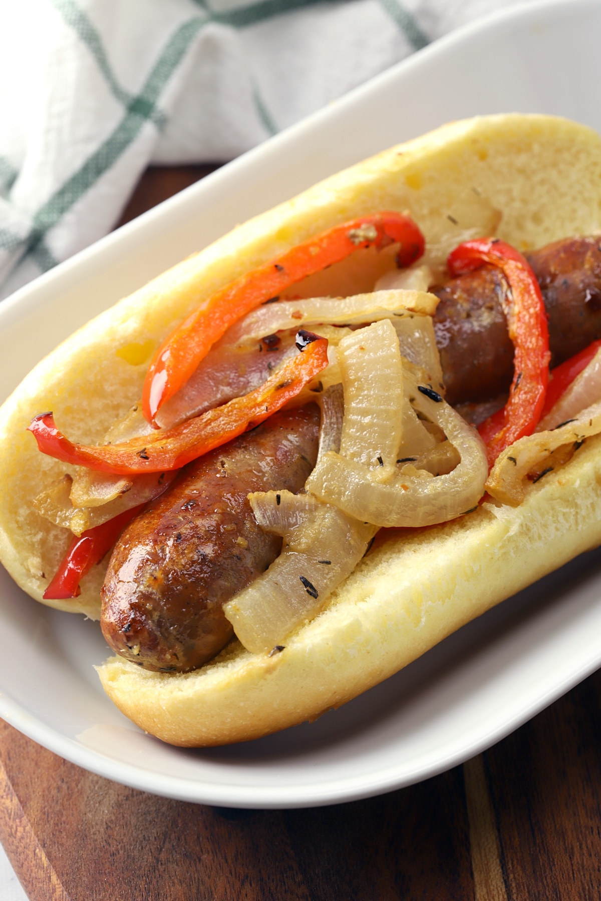 Bratwurst on a hot dog bun, topped with onions and peppers.