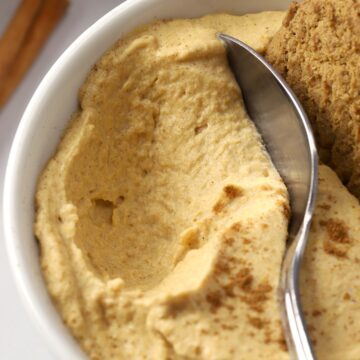 A metal spoon scooping into a bowl of pumpkin mousse.