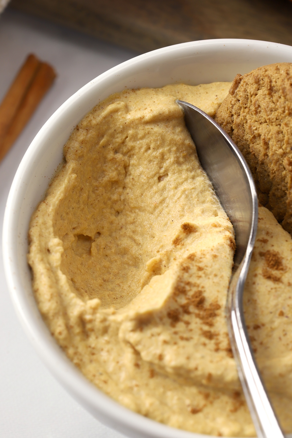 A metal spoon scooping into a bowl of pumpkin mousse.