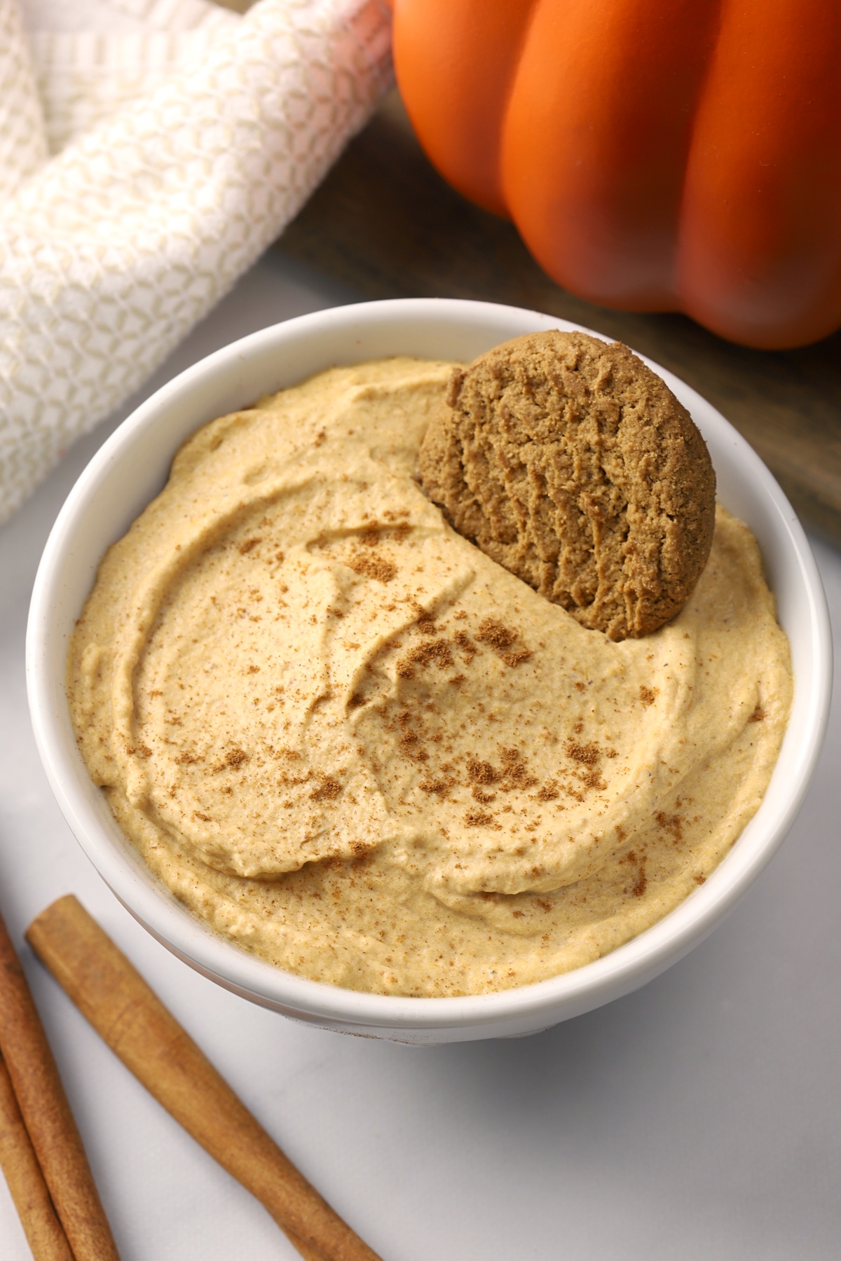 A decorative white bowl filled with pumpkin mousse, decorated with a gingersnap cookie.