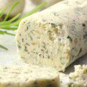 A round log of compound butter filled with herbs and garlic.