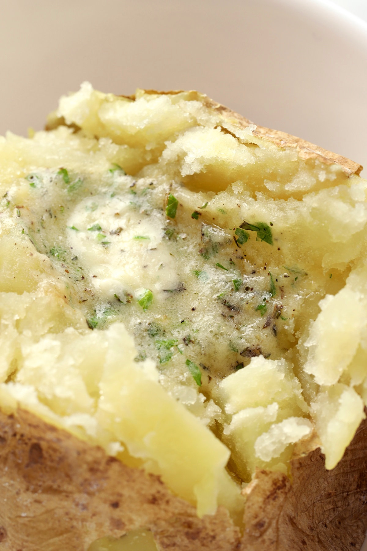 Compound butter melting on top of a baked potato.