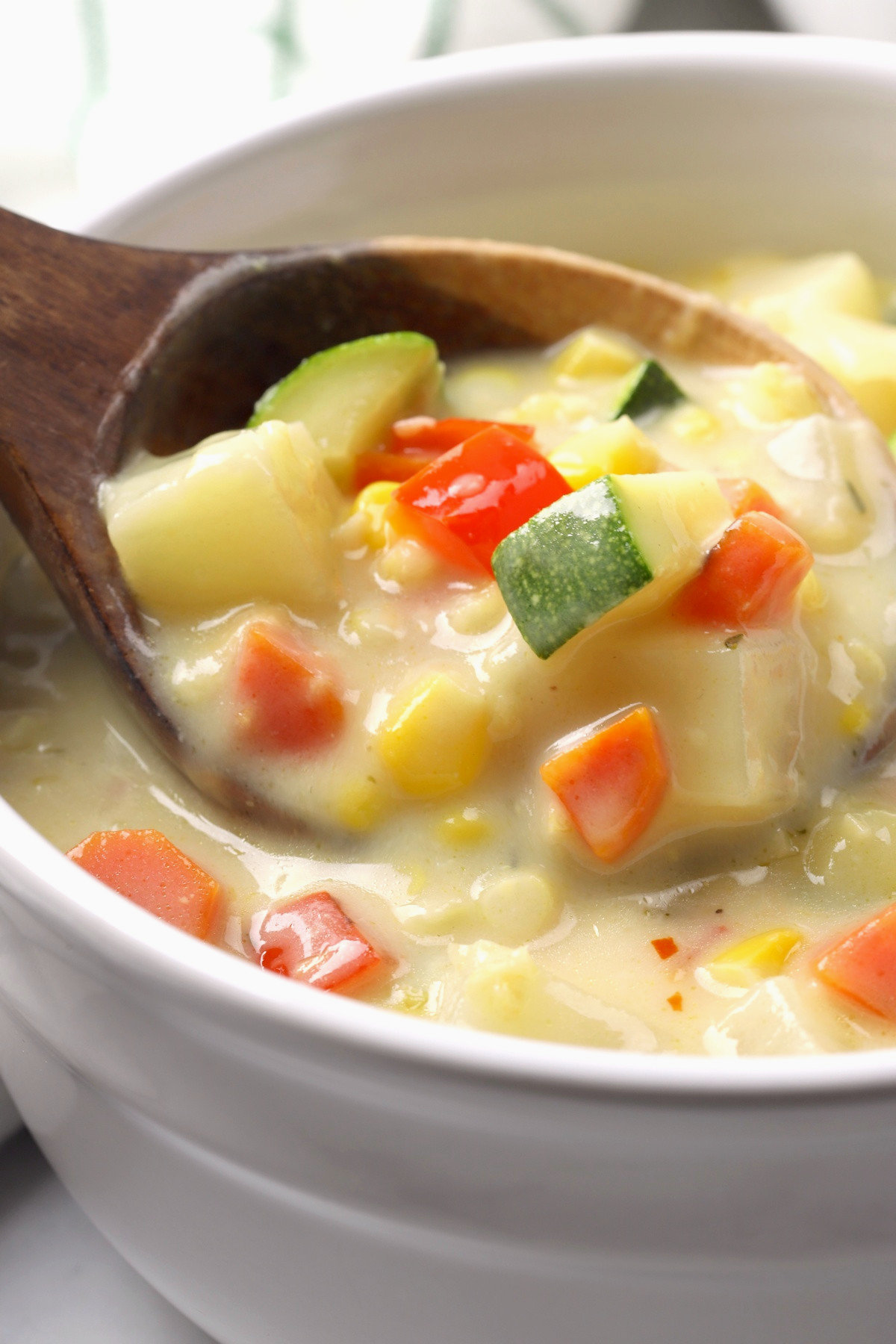 A wooden ladle filled with corn chowder.