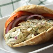Pita bread filled with chicken salad, tomato slices, and red onion.