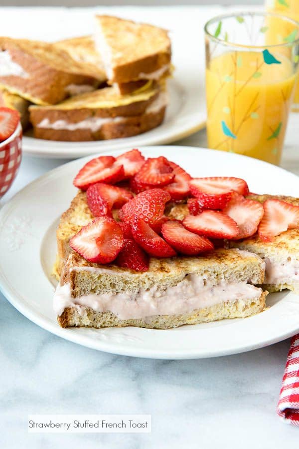 French toast on a plate, topped with fresh strawberries.