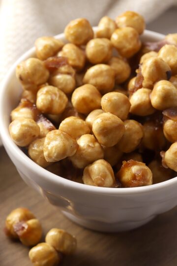 A white decorative bowl filled with candied hazelnuts.