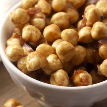 A white decorative bowl filled with candied hazelnuts.