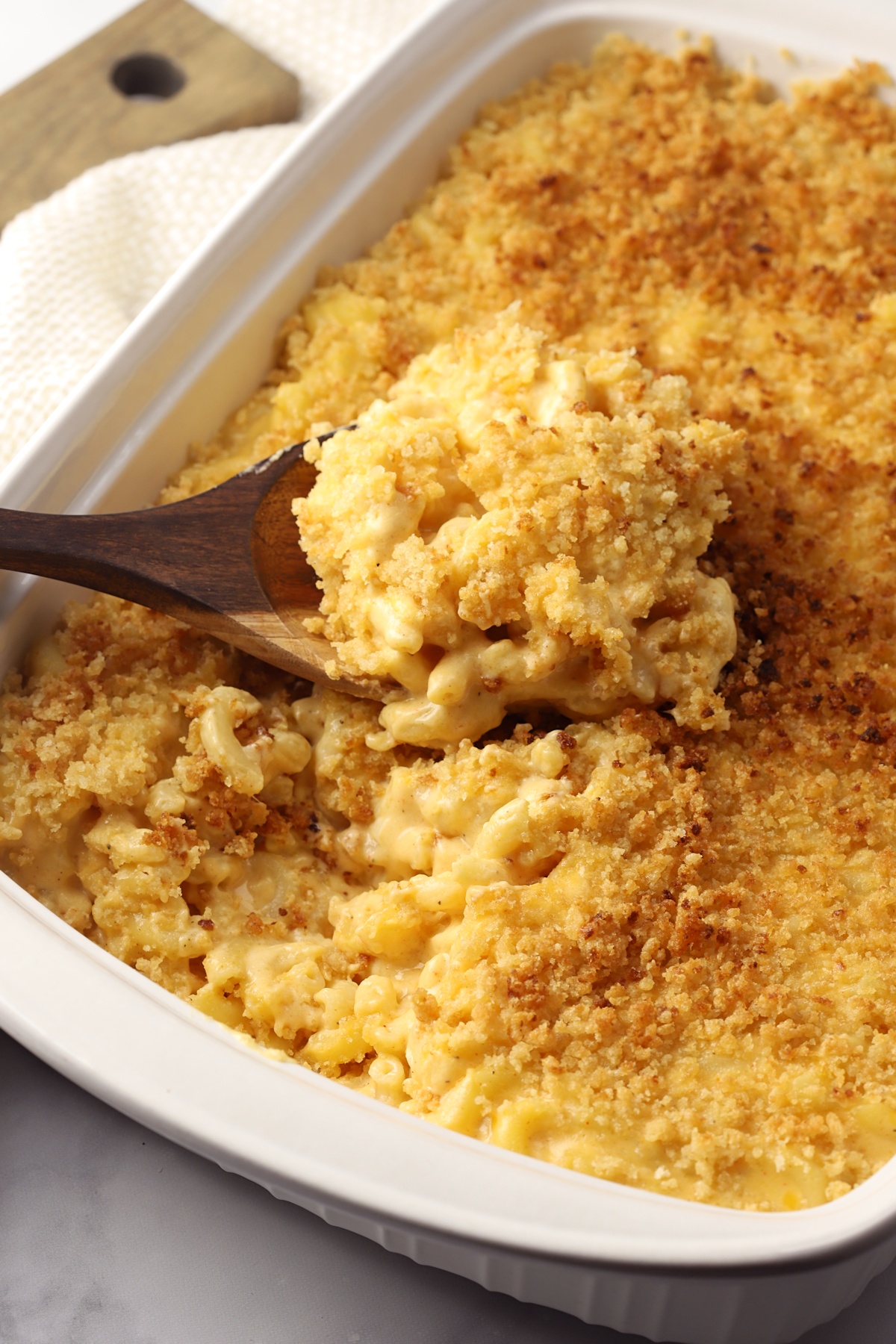 A scoop of macaroni and cheese sitting in a casserole dish.