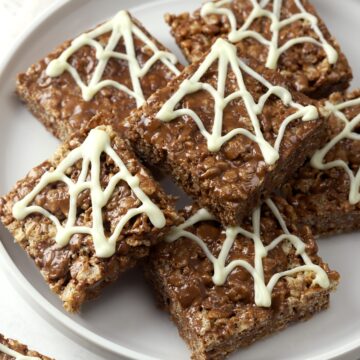 Chocolate rice krispies treats decorated with chocolate spider webs.