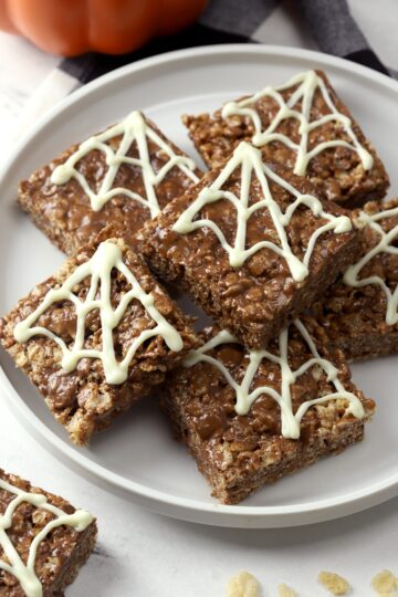 Chocolate rice krispies treats decorated with chocolate spider webs.