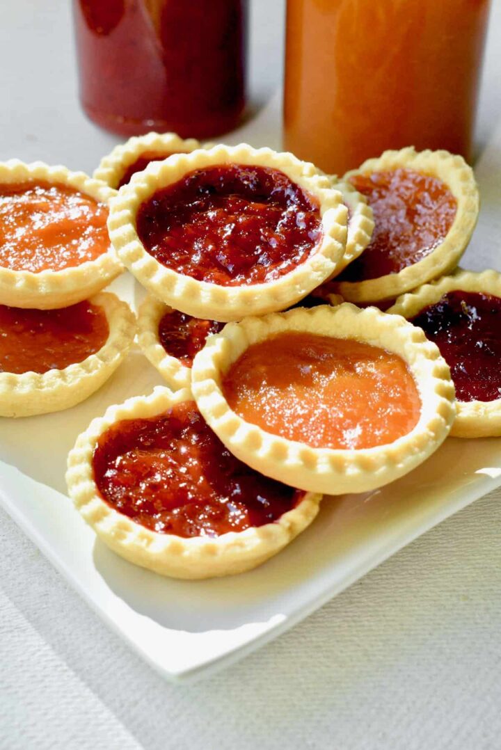 Jam tarts stacked on a white plate.