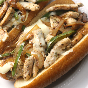 Close up of onion, bell pepper, mushroom, and melty cheese on a chicken cheesesteak.