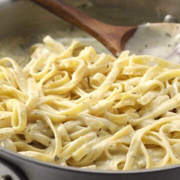 Fettuccine coated in alfredo sauce in a pan.