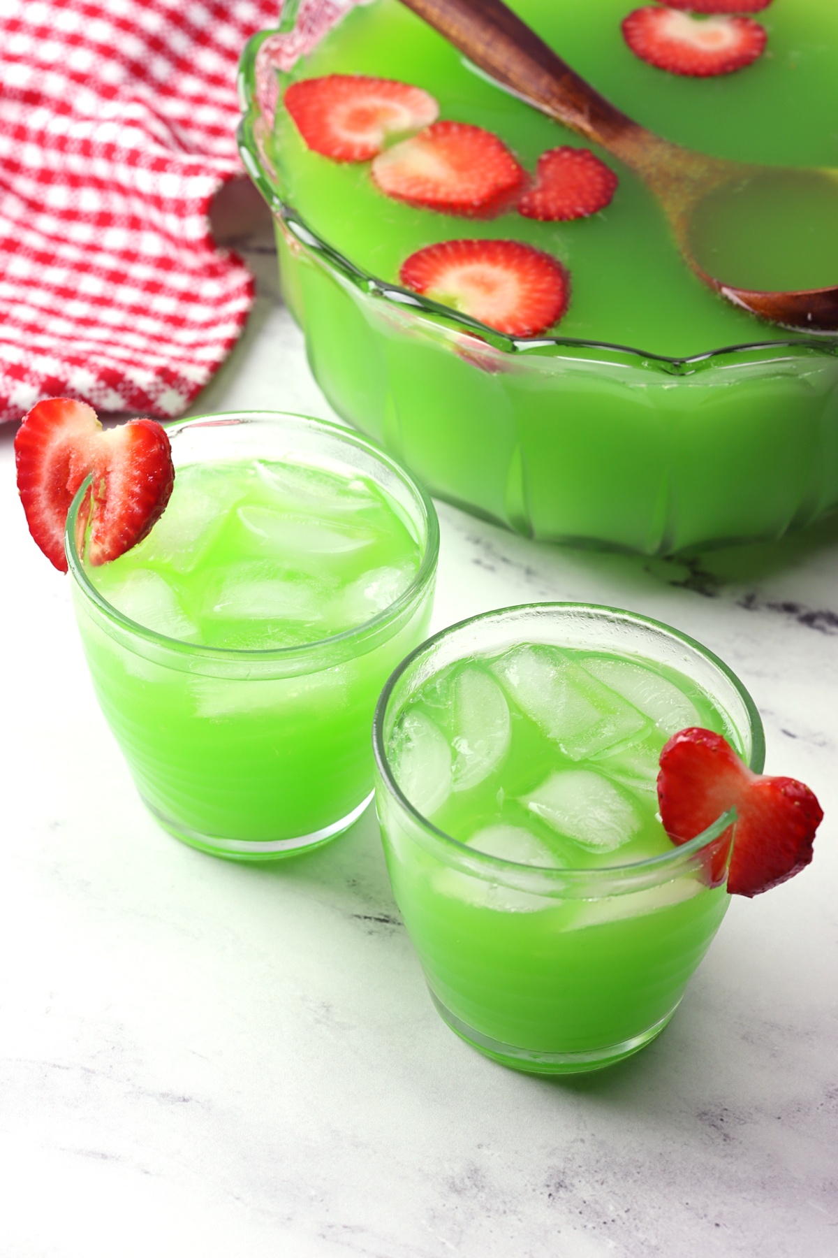 Bowl of punch with two glasses of grinch punch.
