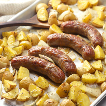 Sheet pan filled with italian sausage and potatoes.