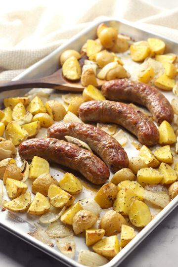 Sheet pan filled with italian sausage and potatoes.