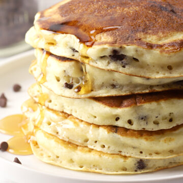 A stack of chocolate chip pancakes on a white plate.