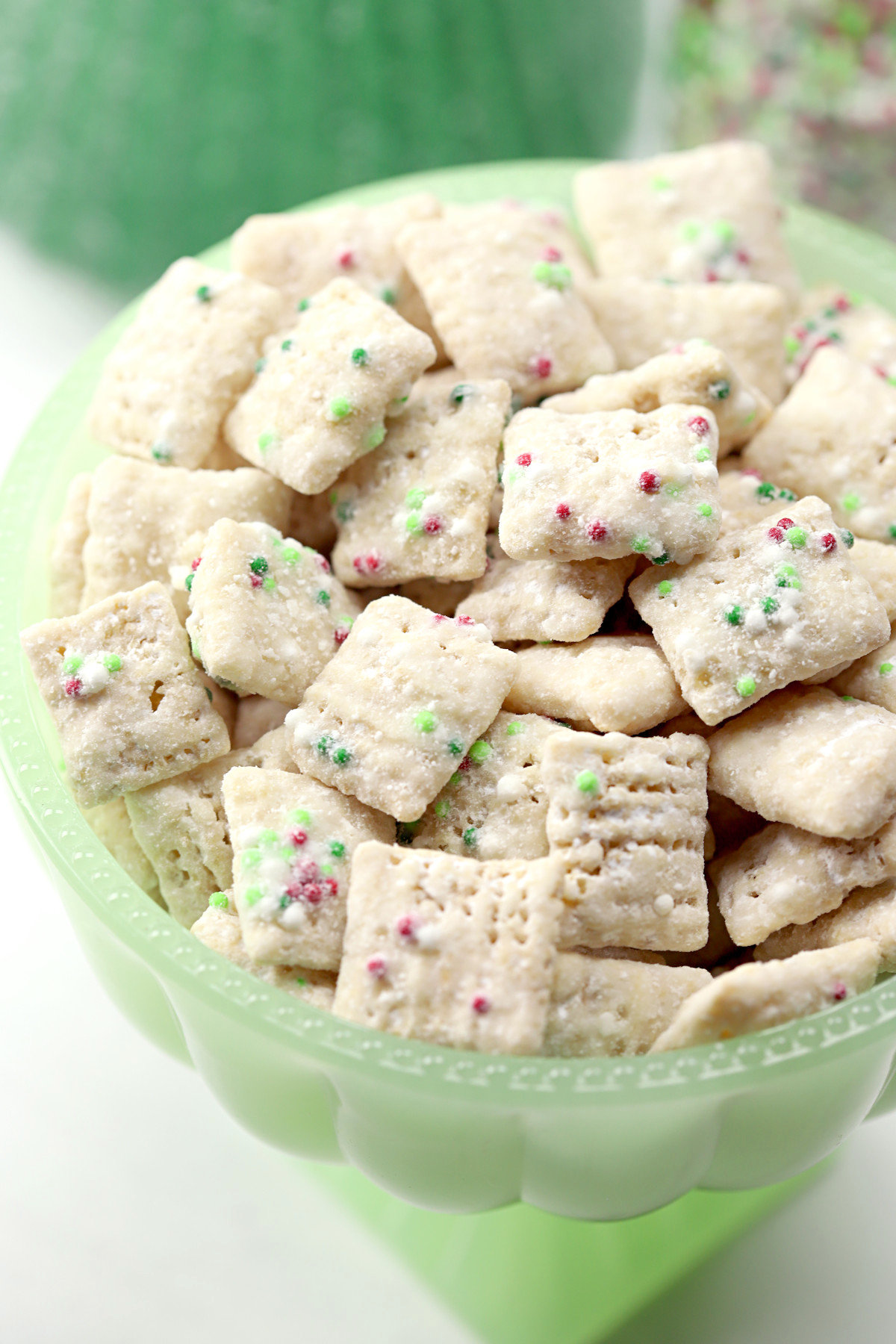 A green bowl filled with Christmas muddy buddies.