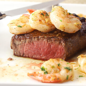 Filet mignon sliced in half and topped with garlic shrimp.